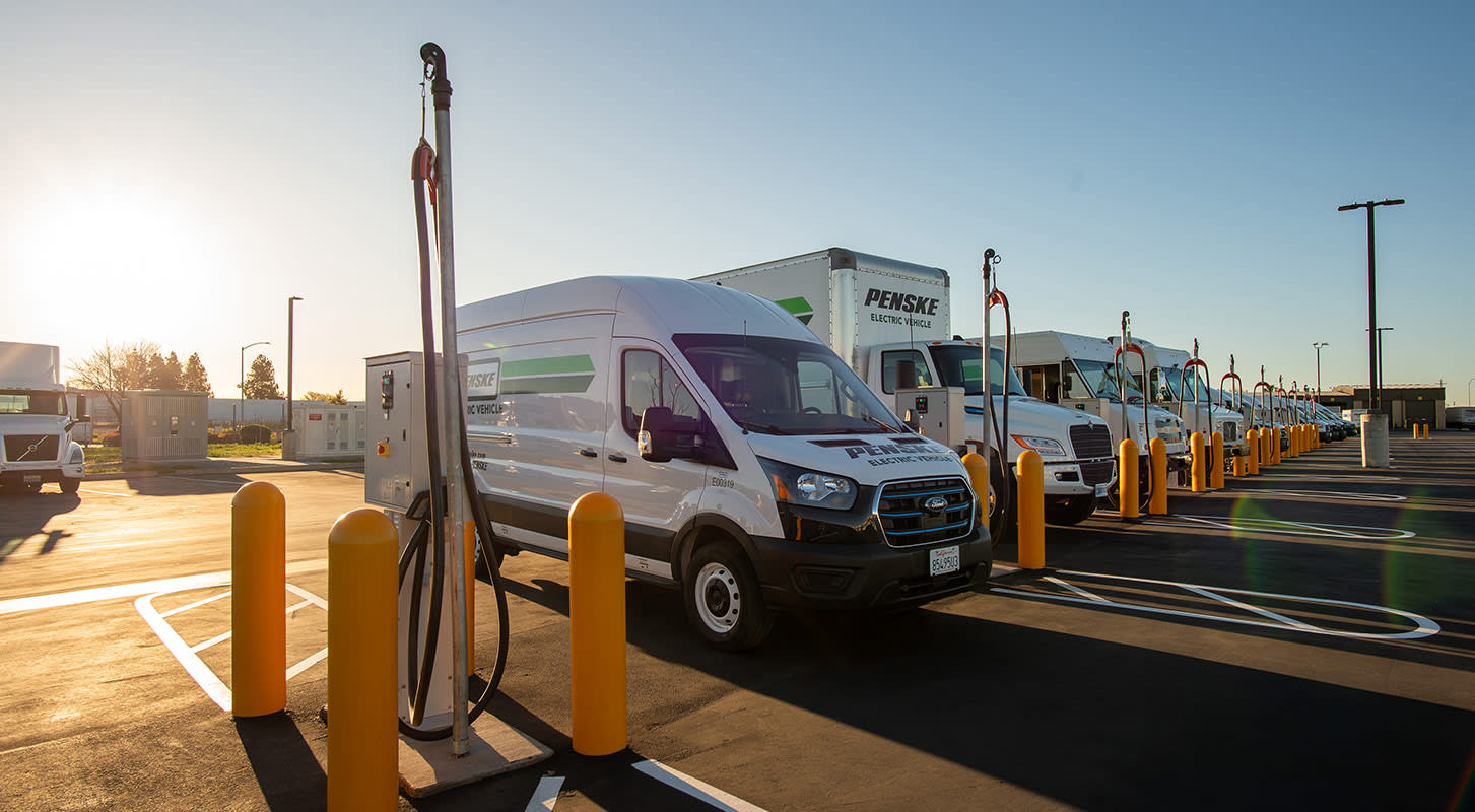 Image of row of Penske vehicles parked at a charging station.